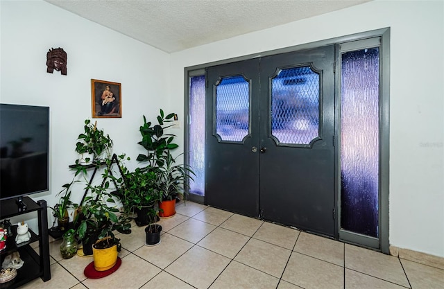 tiled entrance foyer with french doors and a textured ceiling