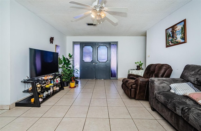 living room featuring ceiling fan, light tile patterned floors, a textured ceiling, and french doors