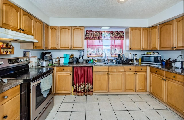 kitchen with a textured ceiling, sink, stainless steel appliances, and dark stone countertops