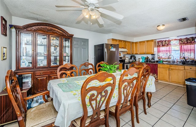 dining room with light tile patterned floors, a textured ceiling, ceiling fan, and sink