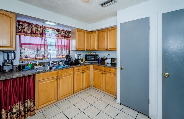 kitchen featuring sink, light tile patterned flooring, and a textured ceiling