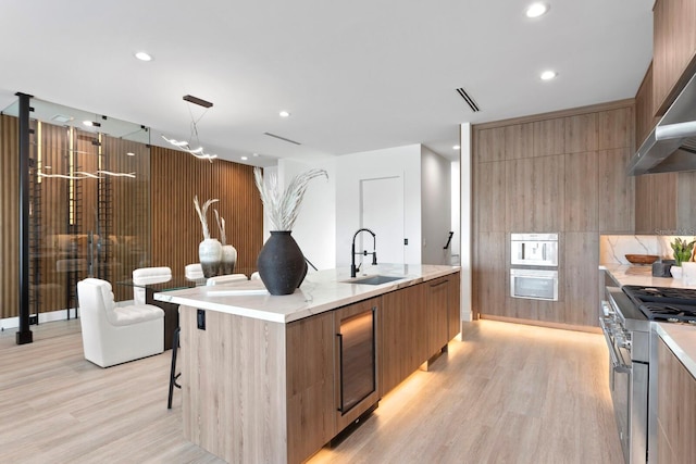 kitchen featuring sink, a breakfast bar area, high end range, an island with sink, and decorative light fixtures