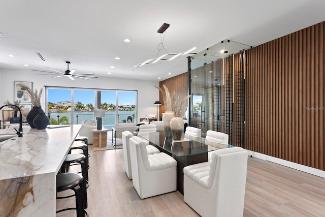 dining room with a water view, ceiling fan, and light wood-type flooring