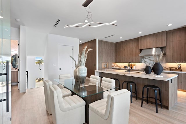 dining space with a notable chandelier, sink, and light wood-type flooring