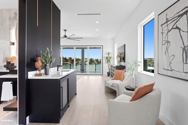 interior space with light hardwood / wood-style floors, ceiling fan, and a water view