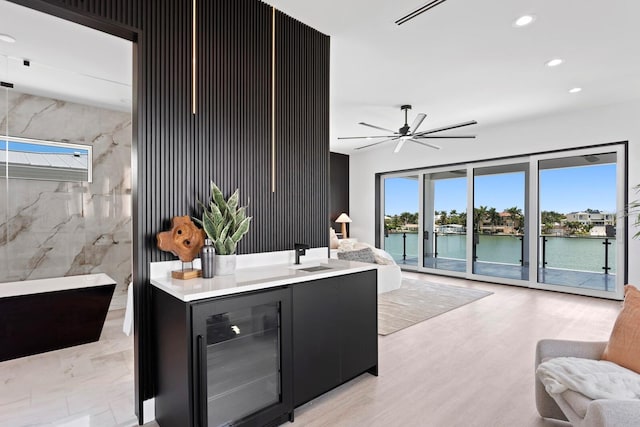 interior space with tile walls, sink, beverage cooler, and a water view