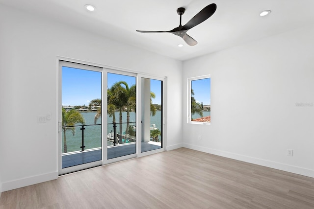 empty room featuring a water view, ceiling fan, and light hardwood / wood-style flooring