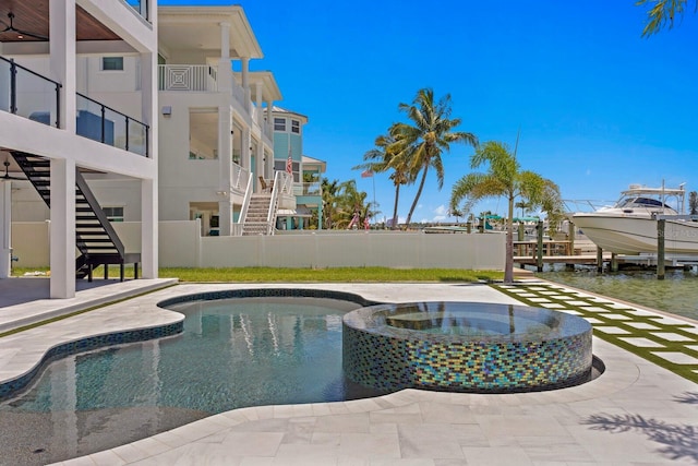 view of swimming pool with an in ground hot tub, a water view, and a patio