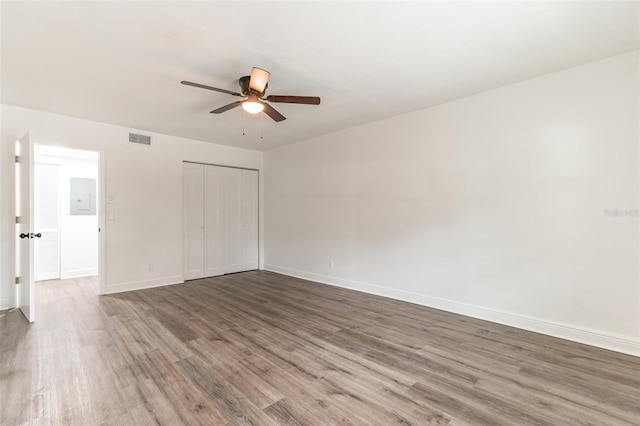 unfurnished bedroom featuring wood-type flooring, electric panel, ceiling fan, and a closet