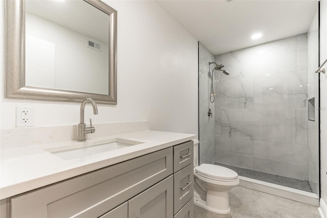 bathroom featuring vanity, toilet, and tiled shower