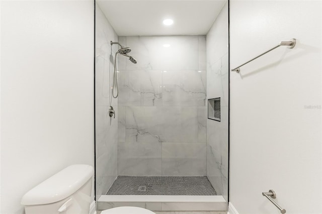 bathroom featuring tiled shower and toilet