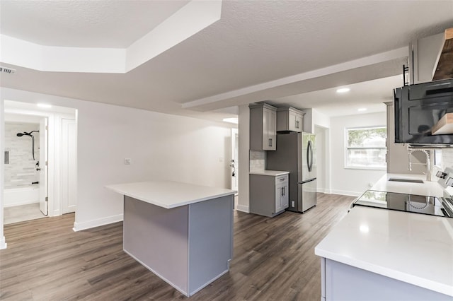 kitchen featuring light countertops, dark wood-style flooring, freestanding refrigerator, and gray cabinetry