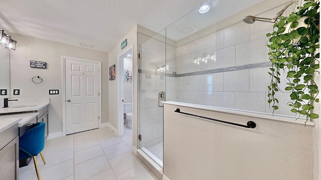 bathroom featuring tile patterned floors, vanity, a textured ceiling, a shower with door, and toilet