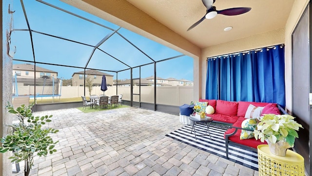 view of patio / terrace with an outdoor living space, a trampoline, ceiling fan, and a lanai