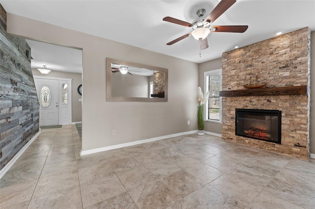 unfurnished living room featuring ceiling fan and a stone fireplace