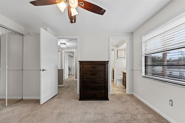 carpeted bedroom with a closet, ensuite bathroom, and ceiling fan