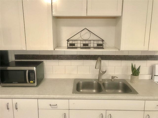 kitchen featuring white cabinetry, stainless steel microwave, and a sink