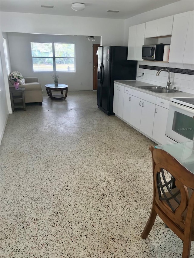 kitchen with white cabinets, black fridge with ice dispenser, white range oven, and sink