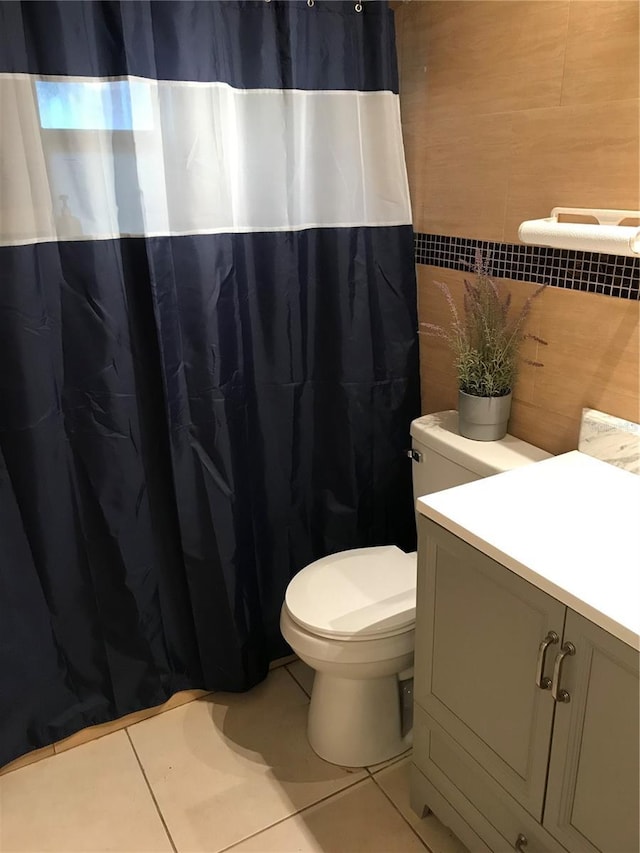 bathroom featuring tile patterned flooring, vanity, toilet, and tile walls