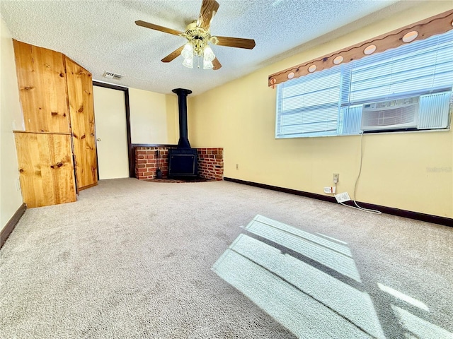 interior space featuring a textured ceiling, ceiling fan, a wood stove, and cooling unit