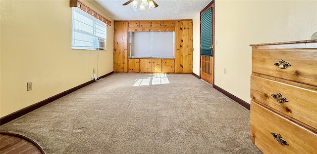 empty room with ceiling fan, light colored carpet, a textured ceiling, and wood walls