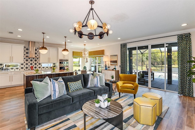 living room featuring light hardwood / wood-style flooring, ornamental molding, and a notable chandelier