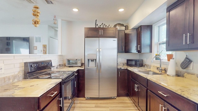 kitchen with tasteful backsplash, light stone counters, sink, black appliances, and light hardwood / wood-style flooring