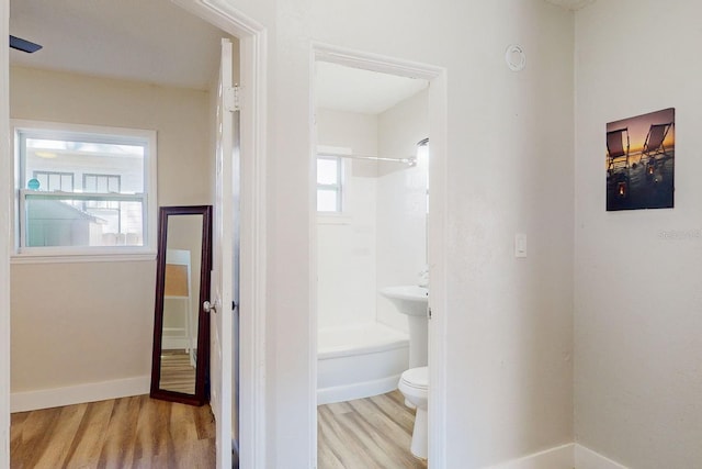 bathroom featuring hardwood / wood-style flooring, toilet, and tub / shower combination