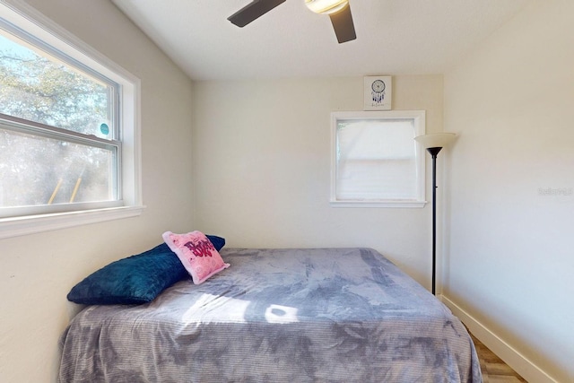 bedroom with multiple windows, ceiling fan, and hardwood / wood-style floors