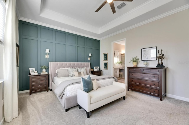 bedroom with ensuite bathroom, ceiling fan, a raised ceiling, and light carpet