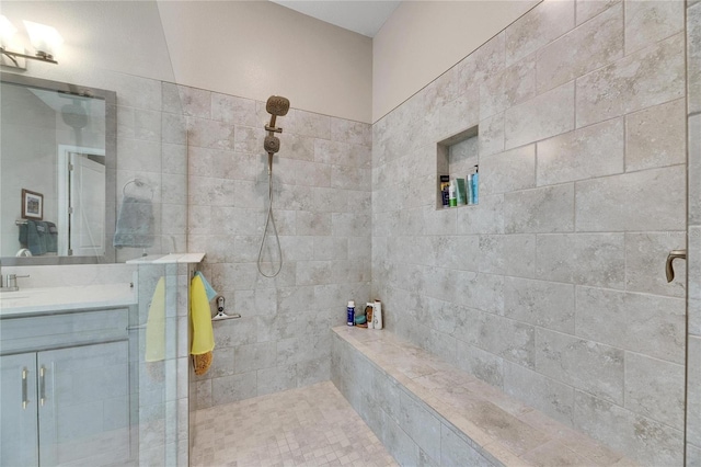 bathroom with tiled shower and vanity