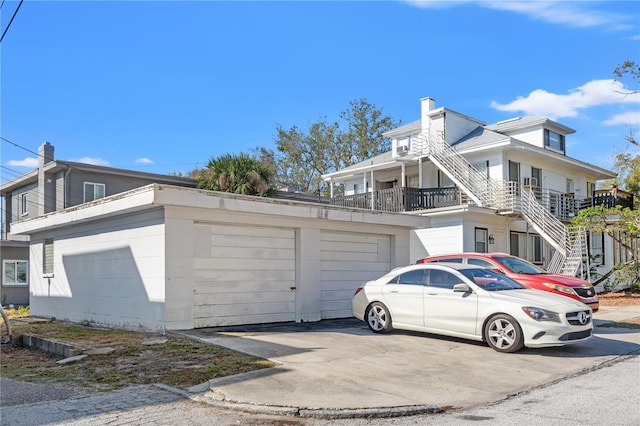 view of side of home featuring a garage, stairway, and a chimney