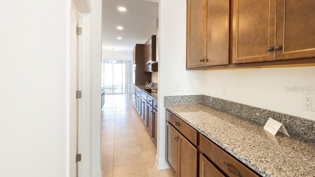 kitchen featuring light tile patterned floors and light stone counters