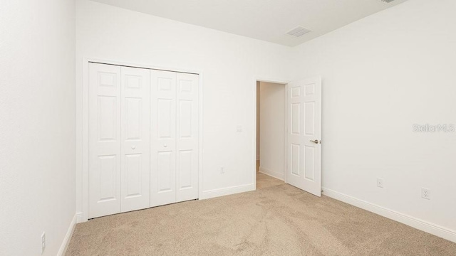 unfurnished bedroom featuring a closet and light colored carpet