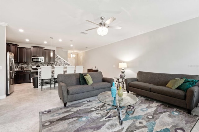 tiled living room with ceiling fan and crown molding