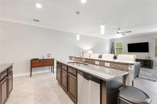 kitchen featuring dishwasher, sink, an island with sink, decorative light fixtures, and light stone counters