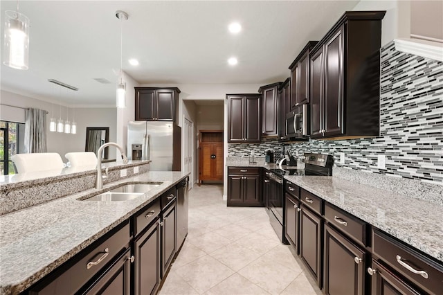 kitchen with light stone countertops, pendant lighting, stainless steel appliances, and sink