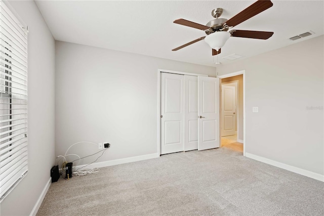 unfurnished bedroom featuring ceiling fan, light carpet, and a closet