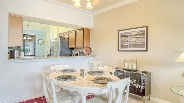 dining room with sink, a chandelier, and ornamental molding