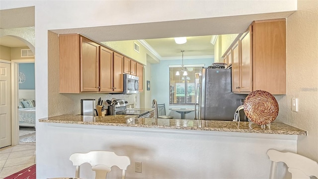 kitchen featuring appliances with stainless steel finishes, crown molding, light stone counters, and hanging light fixtures