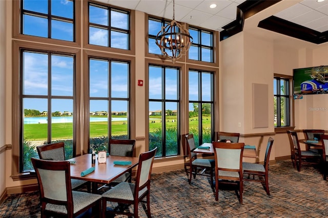 dining space with a water view, a towering ceiling, and a chandelier