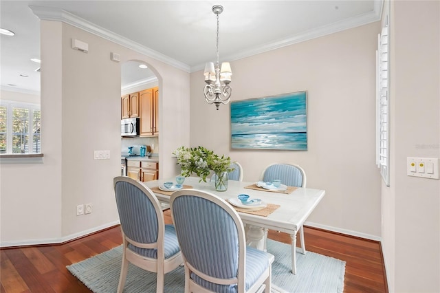 dining area with dark hardwood / wood-style flooring, crown molding, and a chandelier