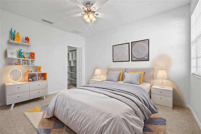 bedroom with ceiling fan, a closet, light colored carpet, and a spacious closet