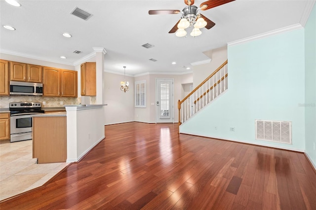 kitchen with appliances with stainless steel finishes, decorative light fixtures, and crown molding