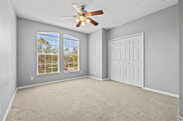 unfurnished bedroom with ceiling fan, light colored carpet, and a closet