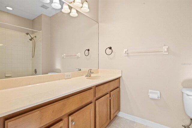 bathroom featuring tile patterned flooring, vanity, tiled shower, and toilet