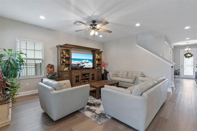 living room featuring ceiling fan with notable chandelier and light hardwood / wood-style floors