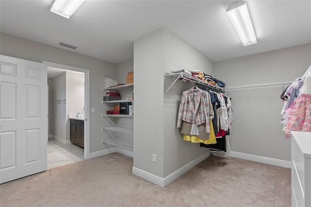 walk in closet with light carpet