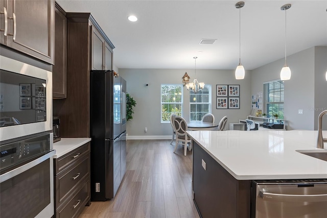 kitchen featuring light hardwood / wood-style floors, a center island, pendant lighting, stainless steel appliances, and a chandelier