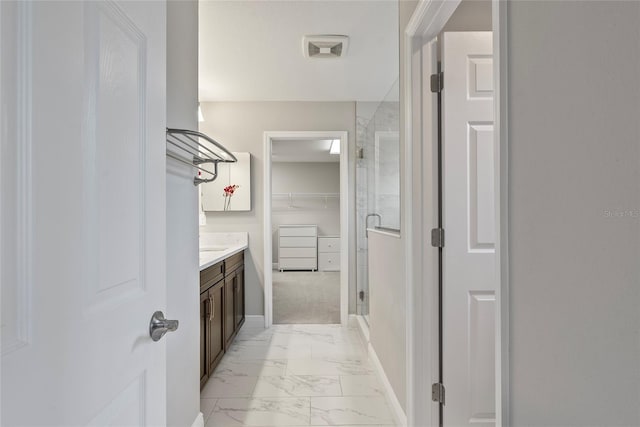 bathroom featuring a shower with shower door and vanity